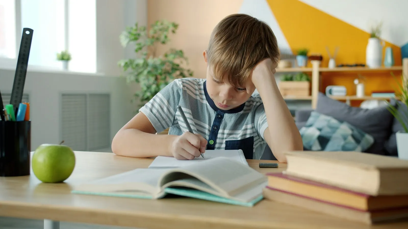 Un jeune garçon concentré fait ses devoirs à un bureau