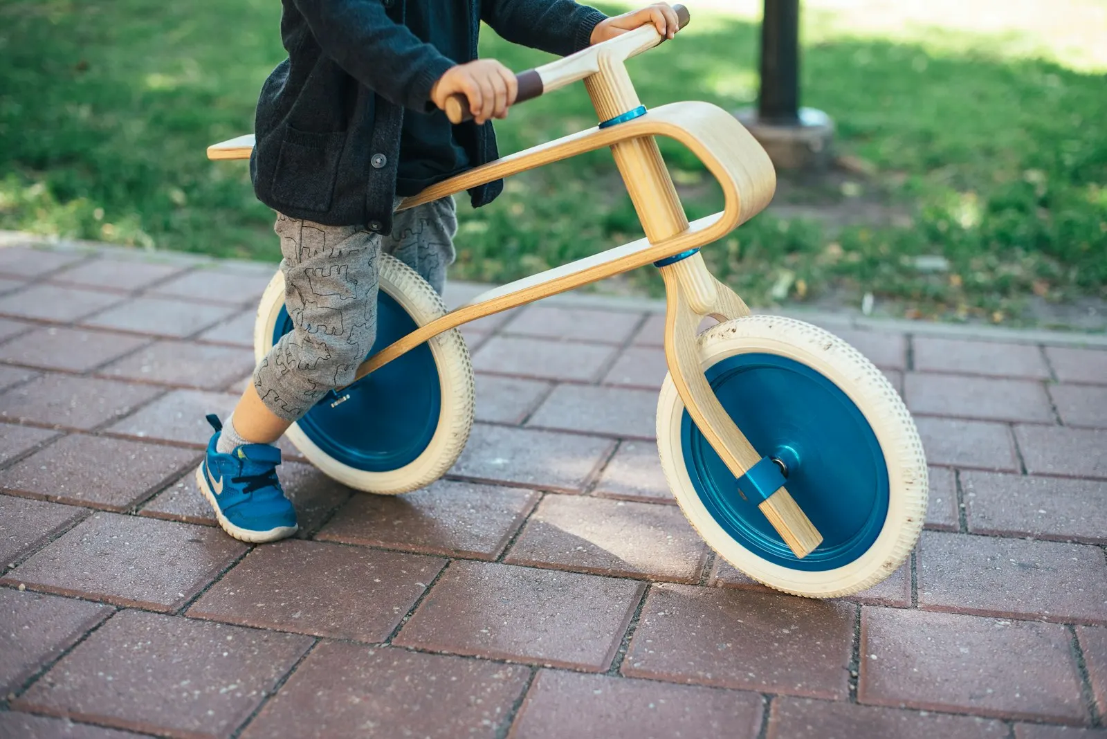 Un jeune enfant roule sur une draisienne en bois