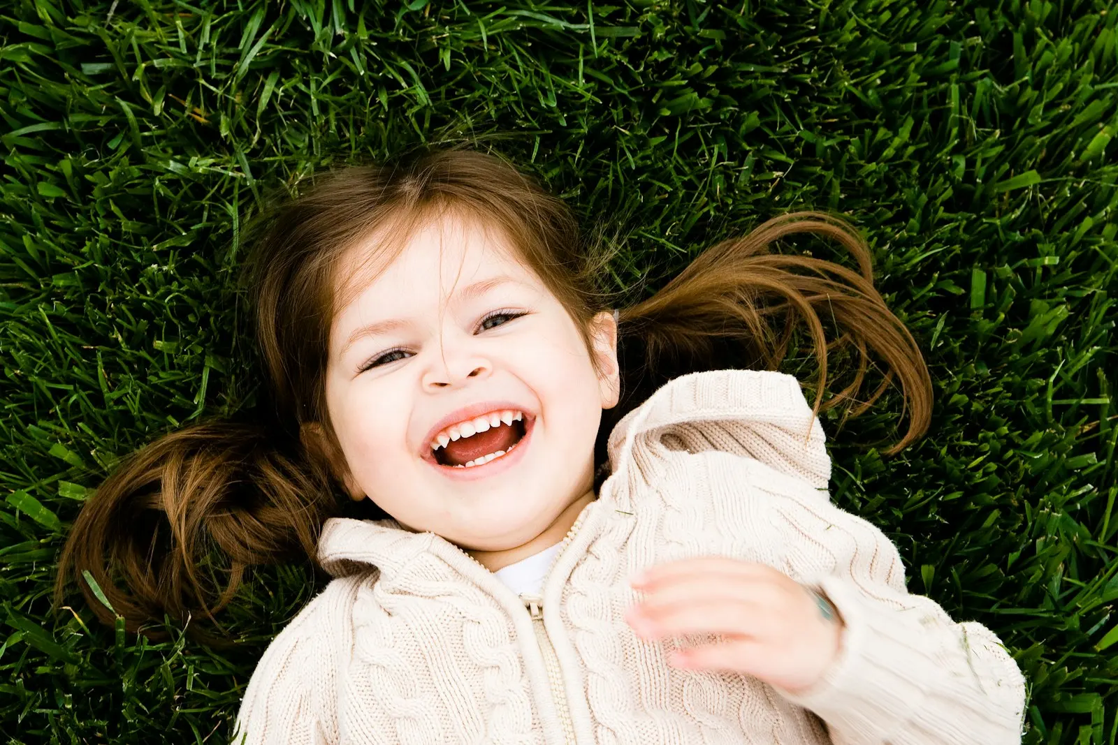 Une petite fille rit, allongée dans l'herbe