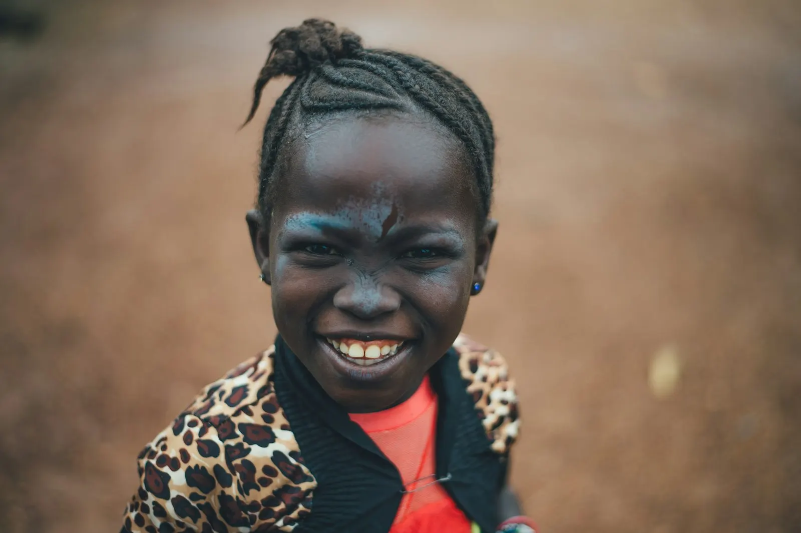 Une petite fille aux cheveux tressés sourit largement à l'objectif