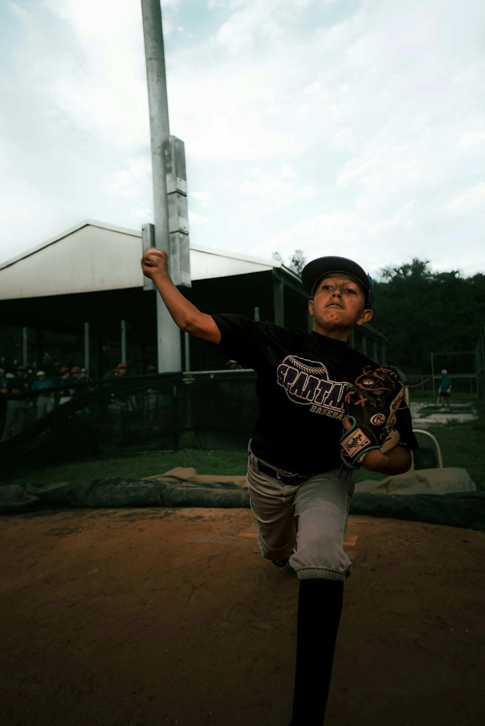 Un jeune garçon en casquette lance une balle sur un terrain de baseball