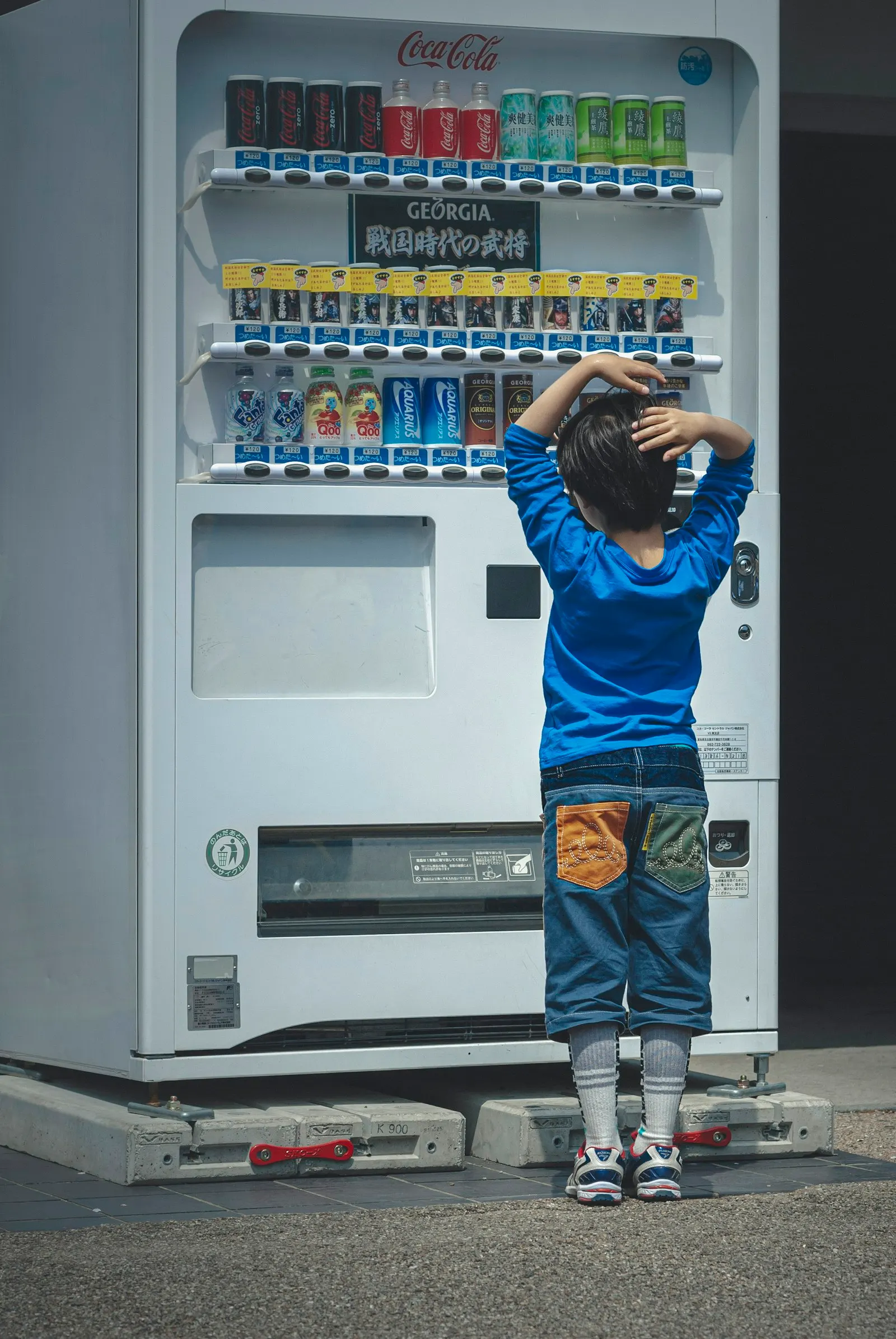 Un petit garçon se tient devant un distributeur de boissons au Japon