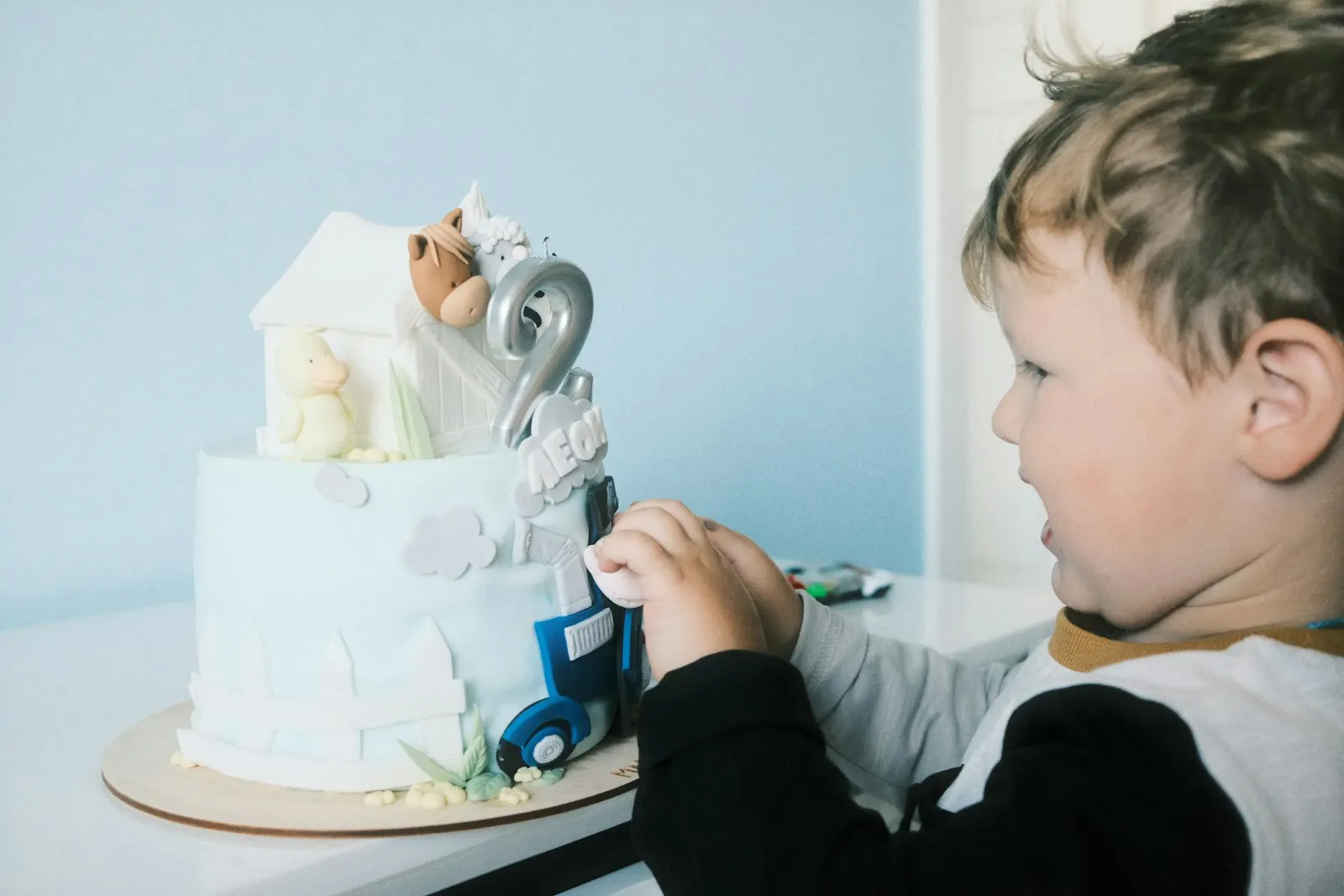 Un jeune garçon décore un gâteau de premier anniversaire