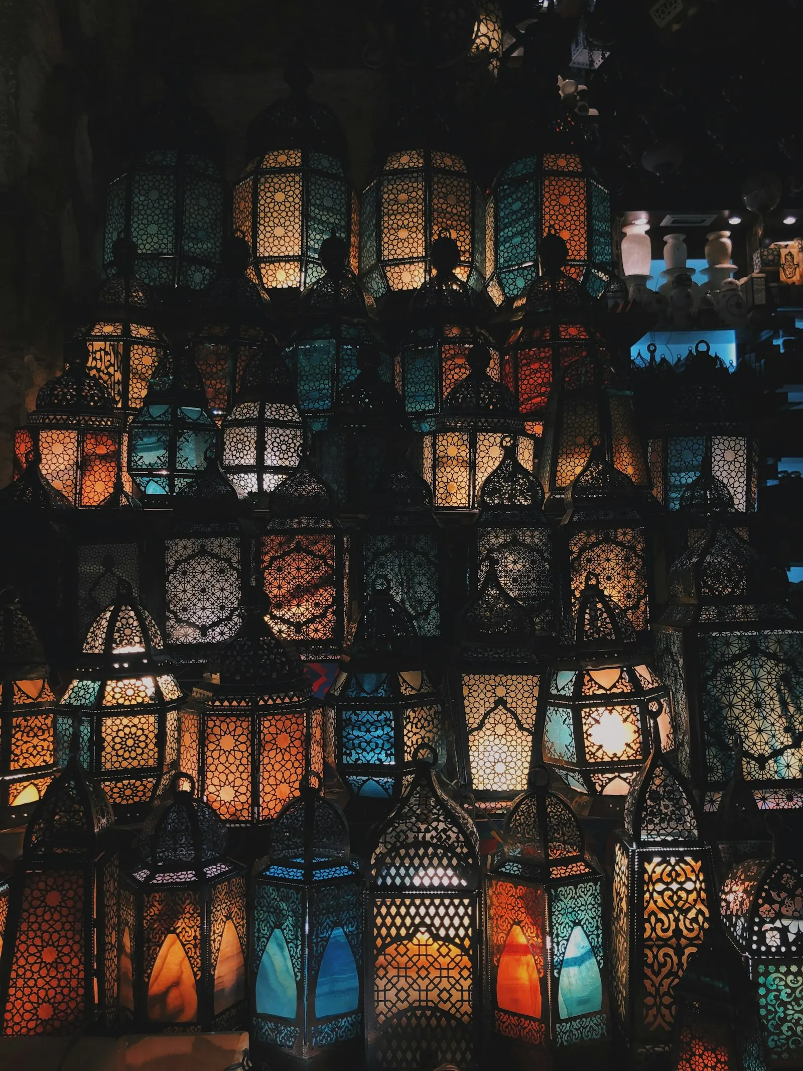 Un mur de lanternes orientales en verre coloré, allumées dans la pénombre