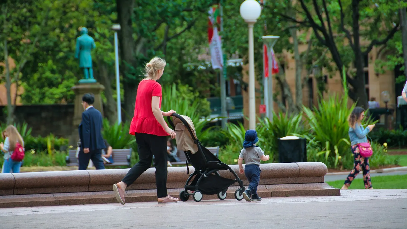 Une femme pousse une poussette avec un enfant dans un parc