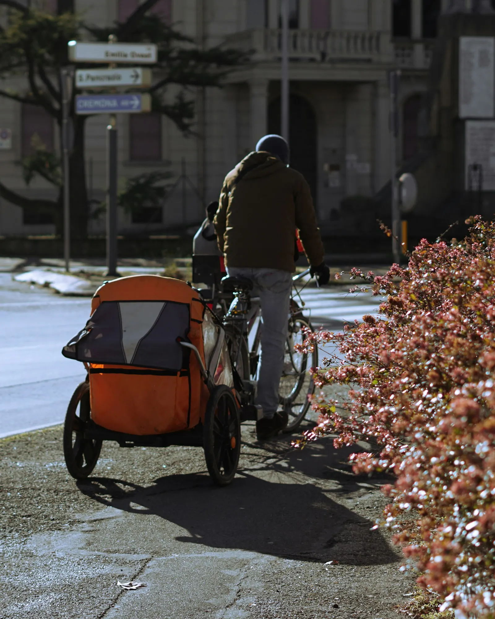 Un cycliste tire une remorque vélo orange pour enfants dans une rue
