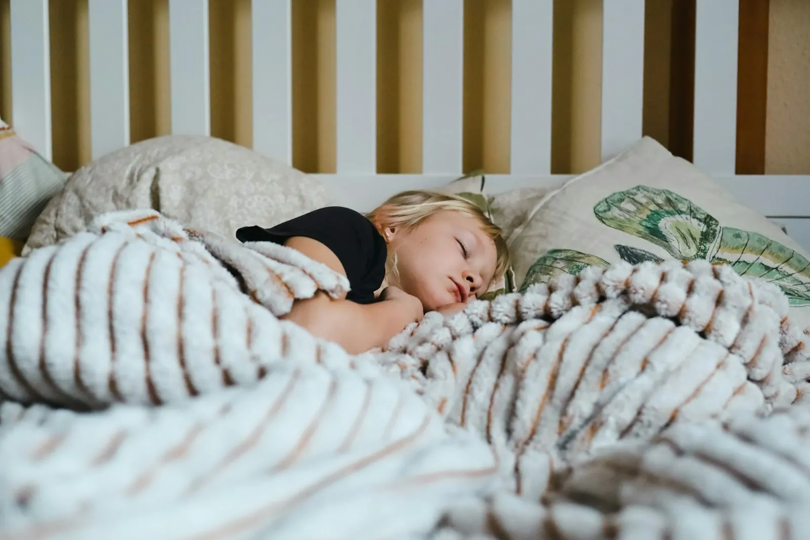 Une petite fille dort dans un lit sous une couverture